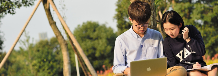 Pair of students relaxing in a garden opposite the Administration Building, Ningbo campus, China 714x249
