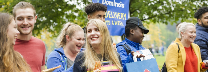 Students eating Dominos at Welcome Fair 2017, outside David Ross Sports Village, University Park 714x249