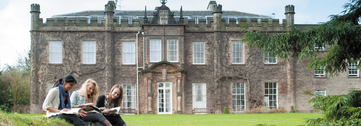 Three female undergraduate students reading historical geography text books outside Hugh Stewart Hall 714x249