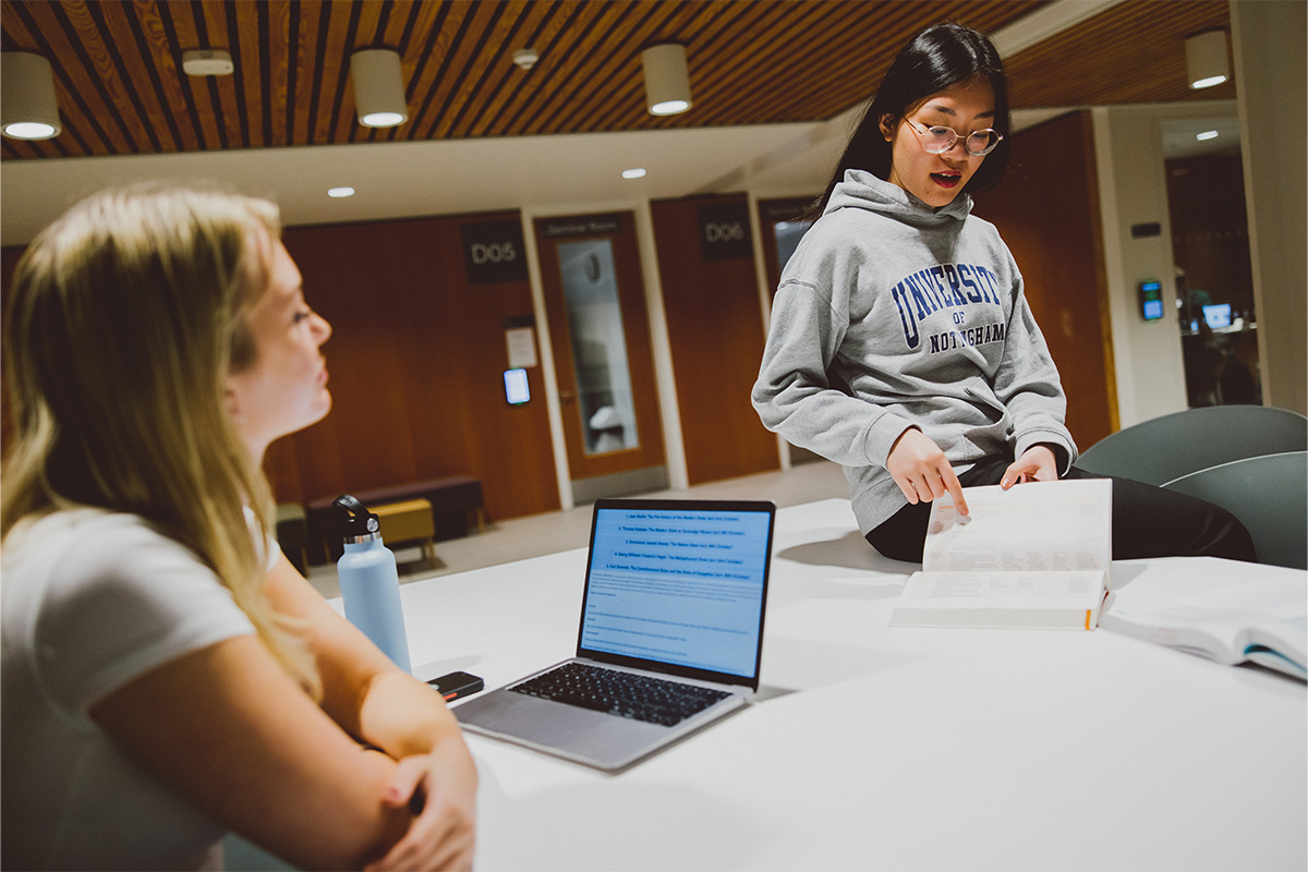 A pair of students studying from books and digital resources