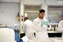 A student working in a chemical engineering lab wearing a lab coat and goggles.