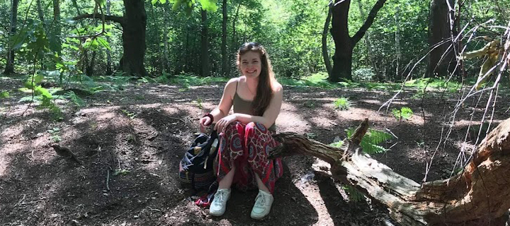 Maddi Maya, sitting smiling in a forest