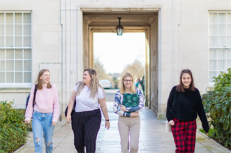 Four students walking through the Trent Building Quad.