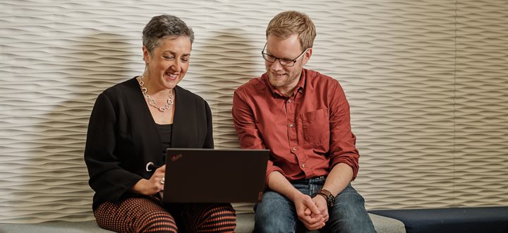 Two people sat looking at a laptop