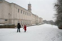 Three students walking in snow in front of Trent Building