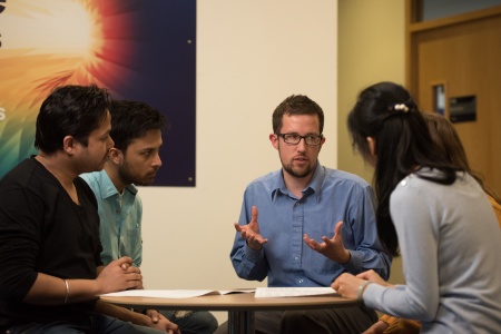 A tutor and three students discussing course material