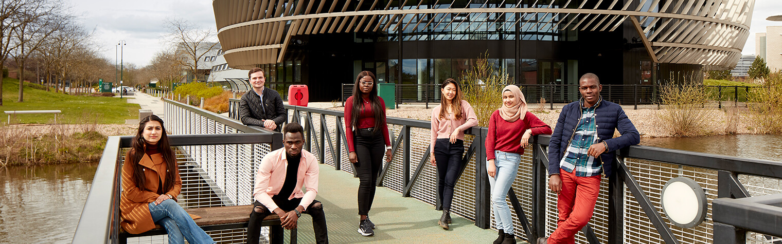Group of students posed over a bridge on campus