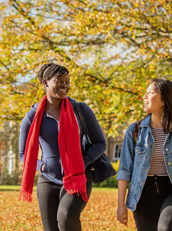 Two students walking through campus, smiling and talking