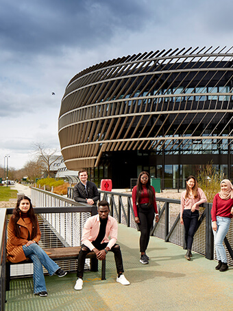 Group of students posed over a bridge on campus
