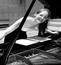 Anne MacGregor standing over a piano, smiling