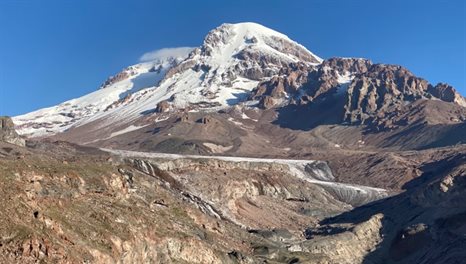 Picture of a snow capped mountain against a bright blue sky.