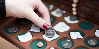 classics-student-looking-at-box-of-coins