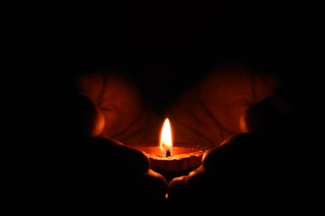 candle in hands in dark place