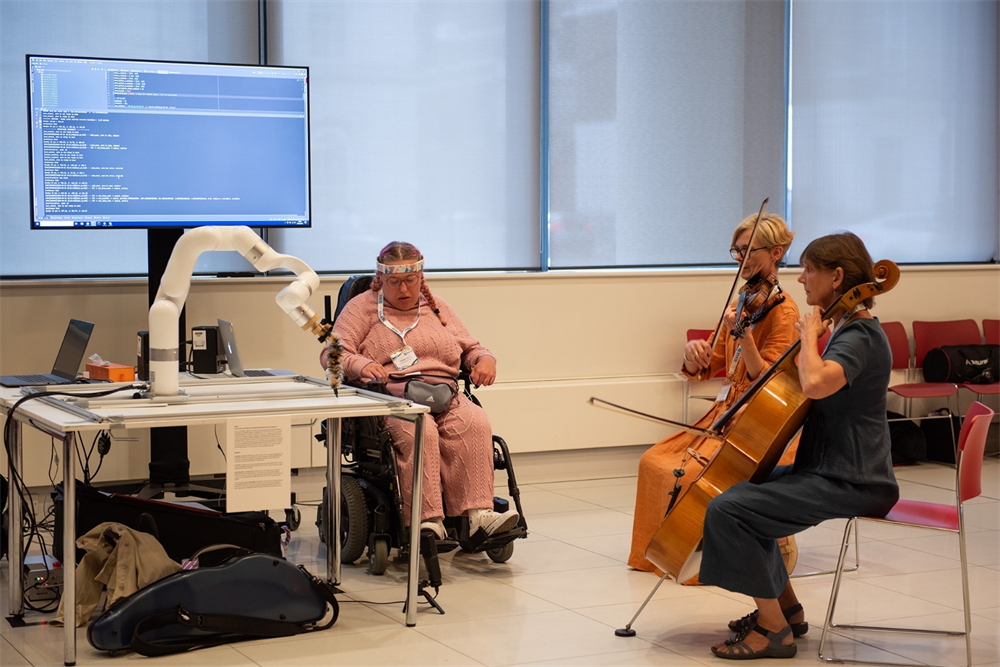 Wheelchair user using robot to collaboratively make music with two string musicians