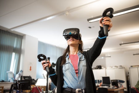 Person using 3D VR Headset with one arm stretched out in front of them.
