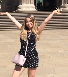 Ciara Murphy standing outside an ancient building with her arms in the air