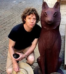 Sascha Auerbach crouched next to a statue of a fox