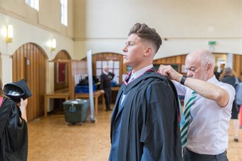Student fixing their graduation gown in place