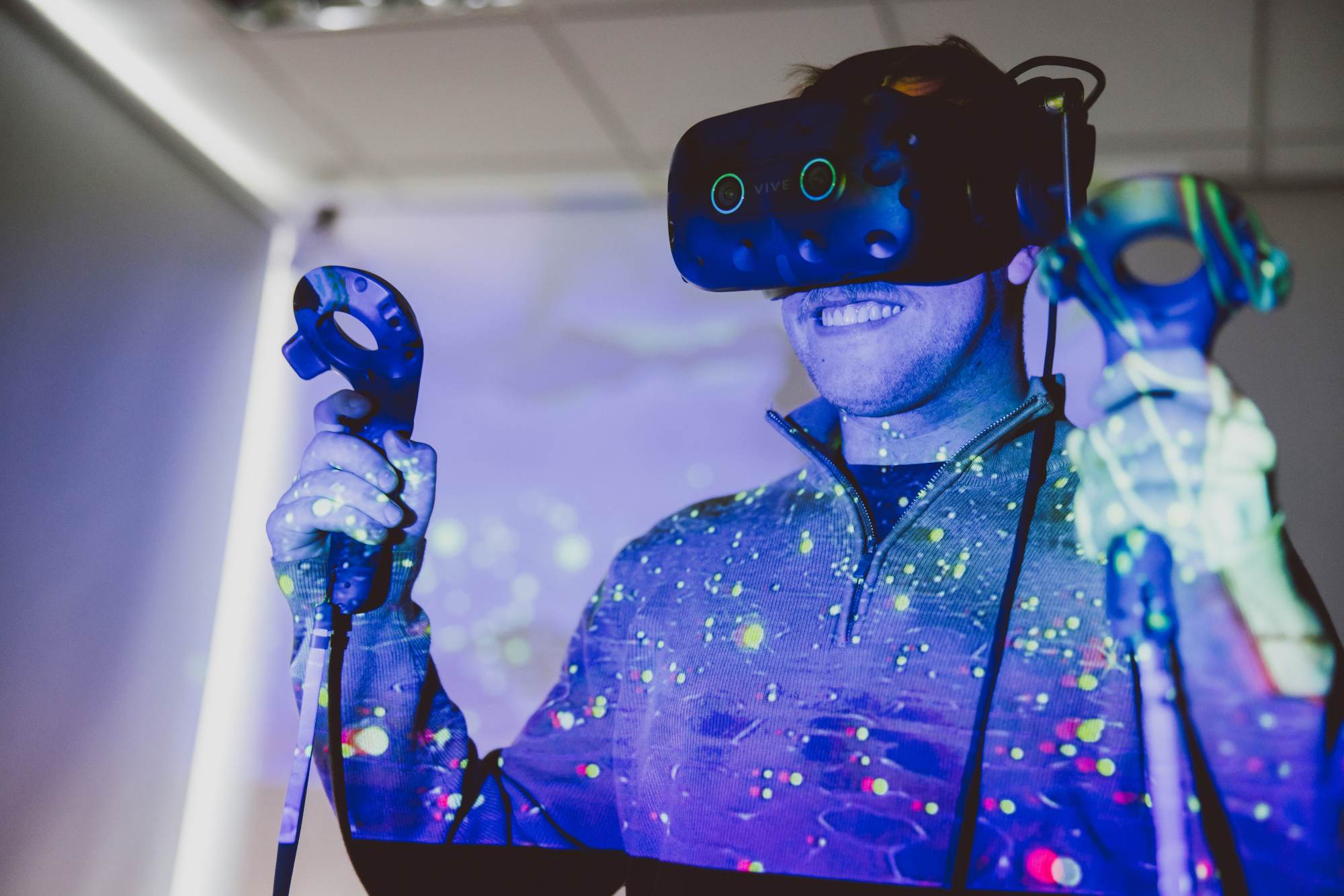 Student wearing VR headset and holding controllers smiling