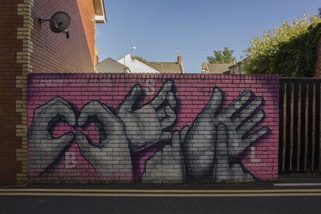 A brightly coloured wall of graffiti depicting hands doing sign language. copy; Jeremy Segrott