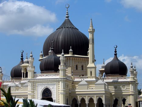 A white and black mosque against a brilliant blue sky