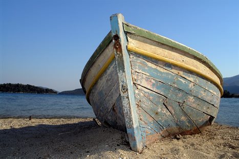 A postcardesque picture of a white row boat on a dreamy sandy beach