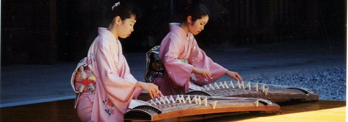 Two ladies in traditional Japanese dress, playing a traditional instrument