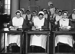 Photograph of nurses sat at desks in a classroom at the Nurses' Memorial Home