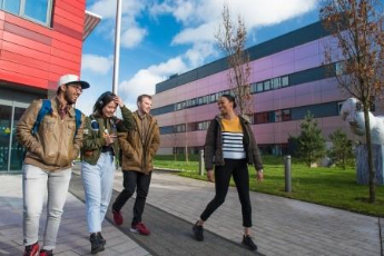 Two male and two female students smiling and chatting on campus