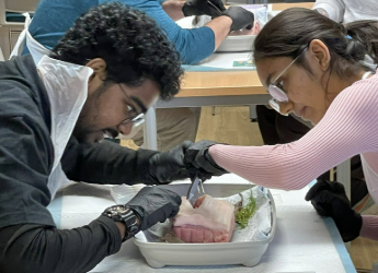 Two sports and exercise medicine students dissecting something.