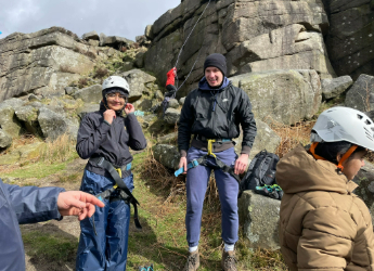 Sports and exercise medicine students wearing climbing gear near a rocky cliff
