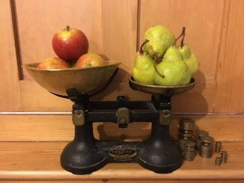 Apples and pears being weighed against each other on a set of scales