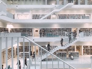 Large white library filled with books and people walking up and down various stairs