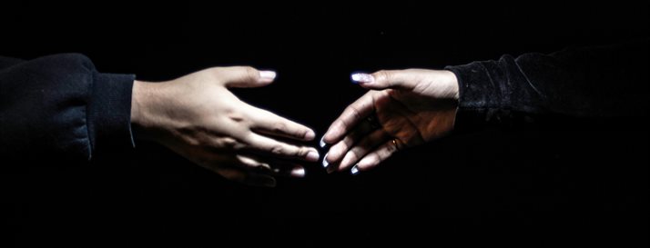 Two hands shaking against a shadowy background