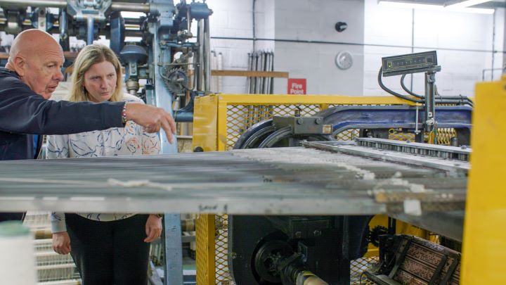 Two people examining a lace machine and the sound it makes