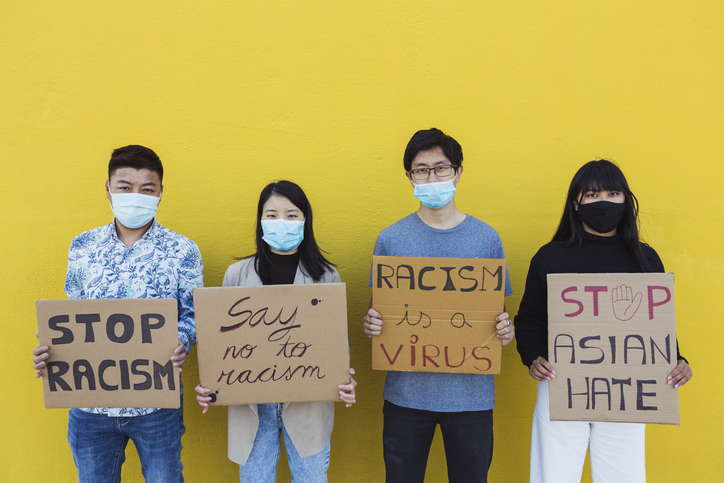 A photo of Chinese and East Asian young people wearing Covid masks and holding Stop Racism placards