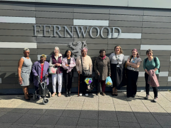 The Grandma’s House team outside Fernwood School. Nine women are shown smiling at the camera, with women from the Afro-Caribbean Elder community, community advocates, University of Nottingham staff and Fernwood School staff