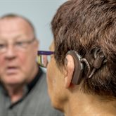 A person with a cochlear implant talks to a person out of focus