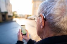A person with a hearing aid undertakes research outdoors using a mobile phone