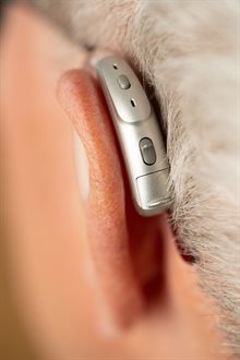 A silver hearing aid behind a left ear
