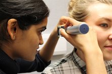 A female clinician using an otoscope on a female participant
