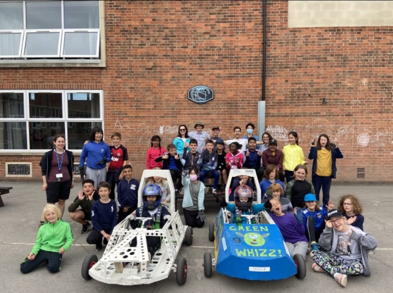 Young children with their teachers, with two small go-carts in front of the group