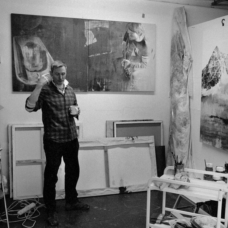 Andy Farr in their studio surrounded by paintings