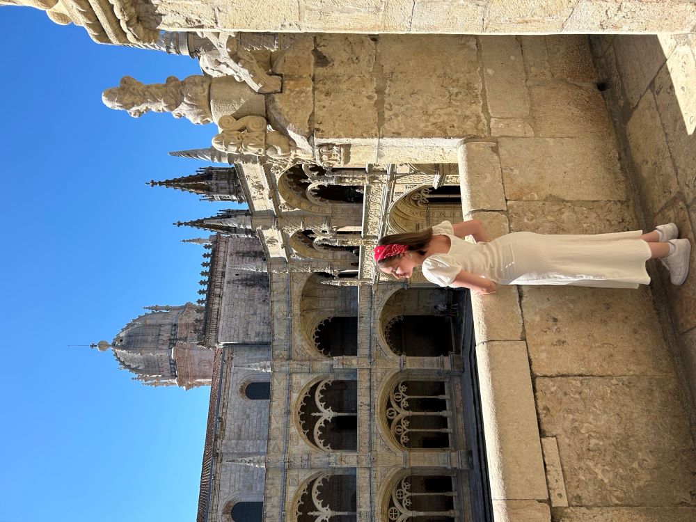 Grace Huxter standing looking over ancient cloistered building in bright sunshine