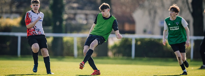 Football players compete on grass pitch