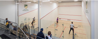 Students playing squash with a crowd watching