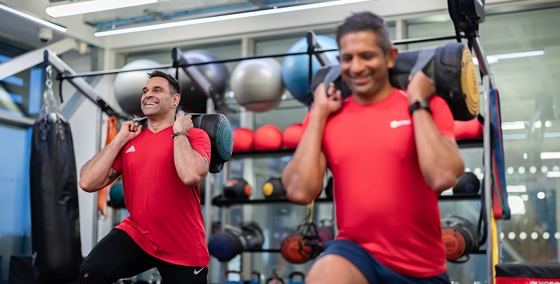 Two members work out smiling with weights