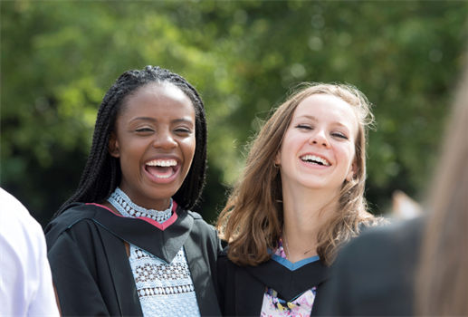 Two graduating students laughing having their photograph taken