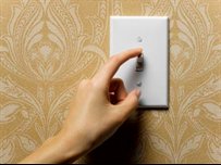 person switching off a light switch on the wall