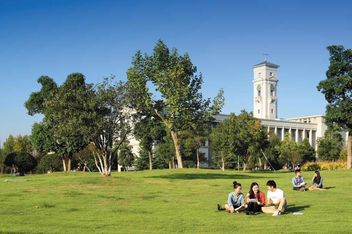 Students sat on the grass in front of the Trent Building at our China Campus in Ningbo